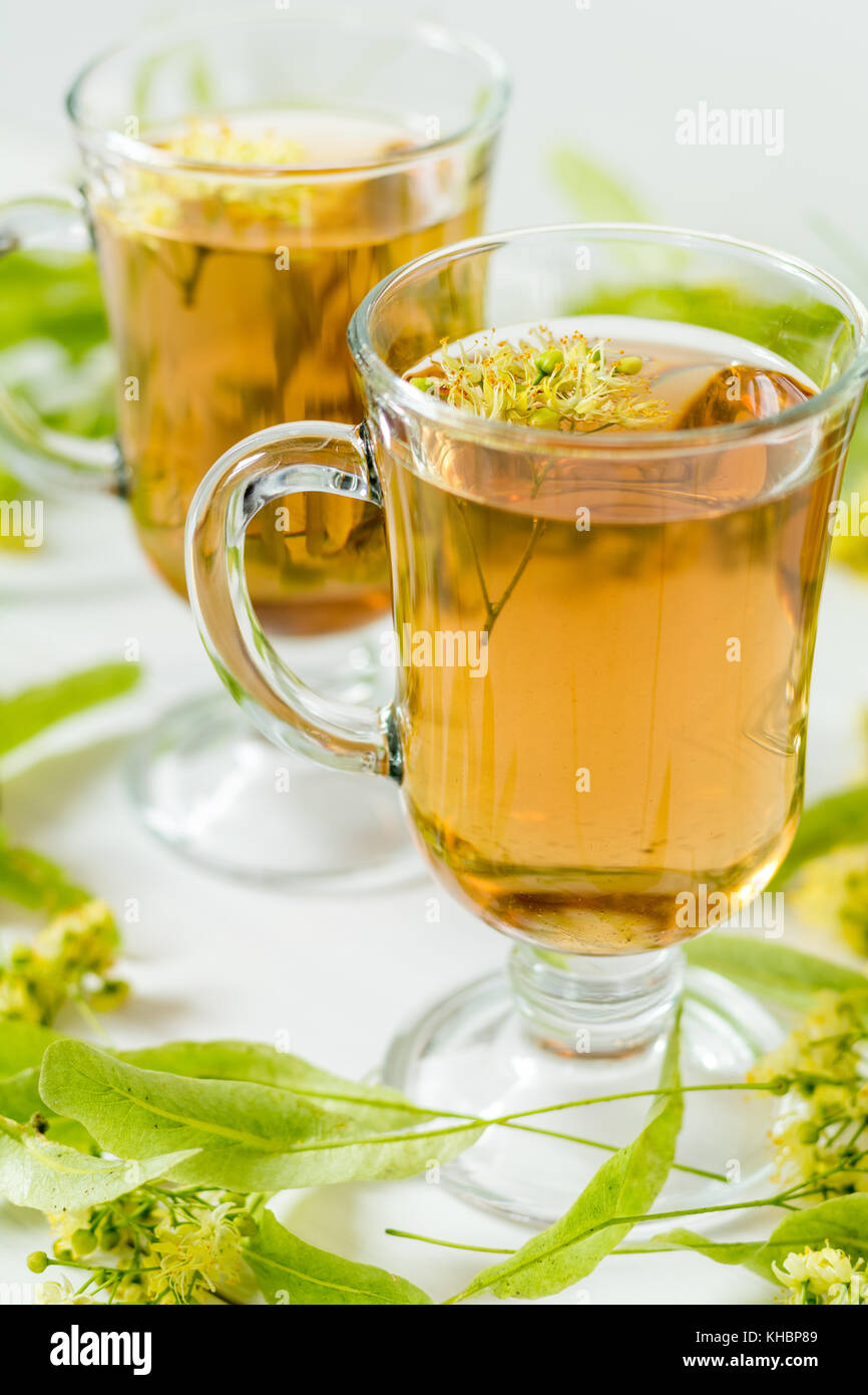 Linden flower tea in a transparent grog glass with a linden blossom on the white wooden surface Stock Photo