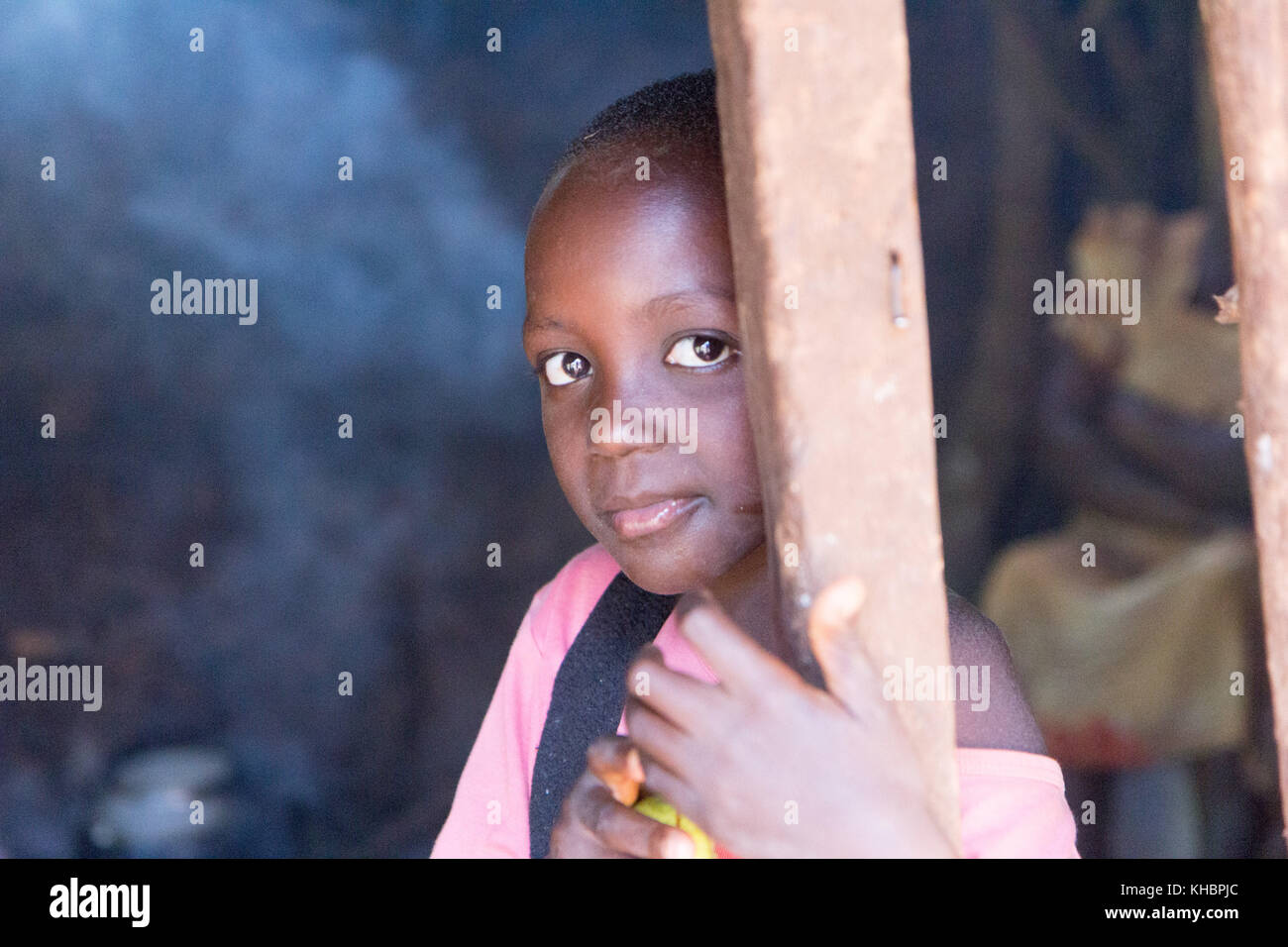 A smiling tween age girl at the door of a smoky kitchen in which food is being prepared. Stock Photo