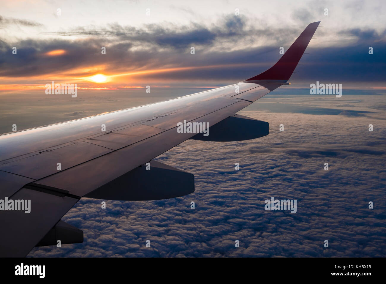 Wing of the airplane, flight over cloud cover, sunset Stock Photo