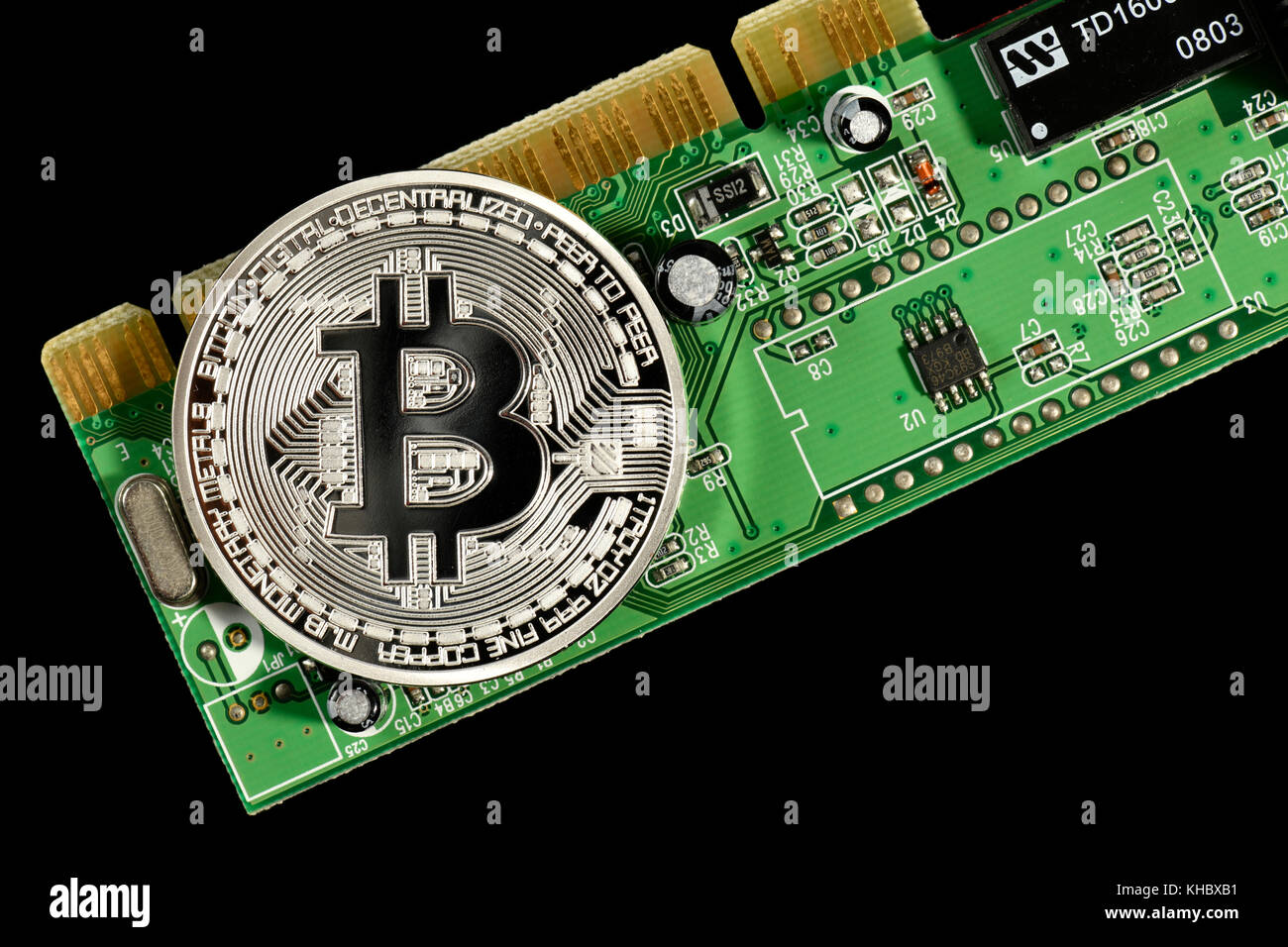 Symbol image digital currency, silver physical coin Bitcoin on printed circuit board Stock Photo