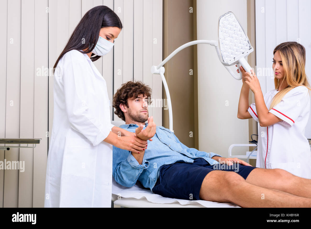 A young male patient in the emergency room getting attended by a female professional physician. Stock Photo