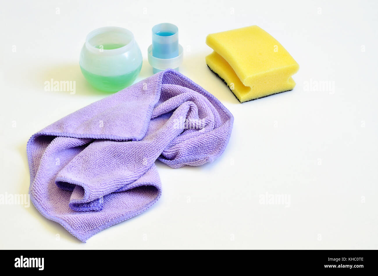 yellow sponge, pink cleaning cloth and dishwashing liquid on white
