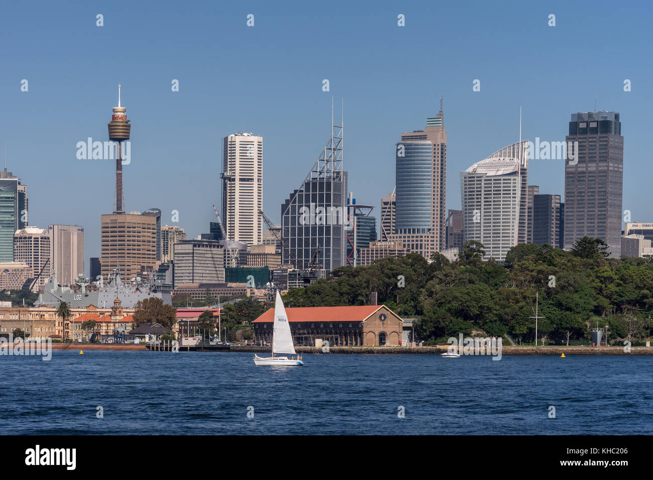 Sydney, Australia - March 26, 2017: Closeup kind of shot of selection of tall office towers skyline seen off the water under blue sky. White sail boat Stock Photo