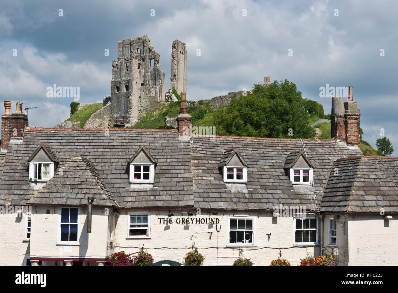 The ruins of Corfe Castle, Devon standing on the hill top overlooking the village of the same name with The Greyhound Public House in the foreground. Stock Photo
