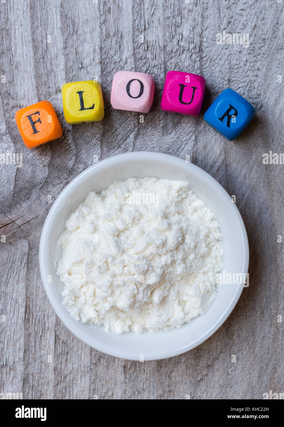 Flour in bowl with letter cube on wooden background. Stock Photo