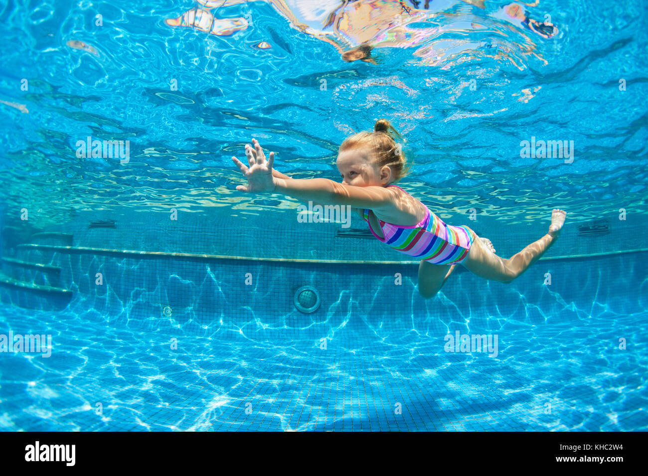 Funny child learn swimming, diving in blue pool with fun jumping deep