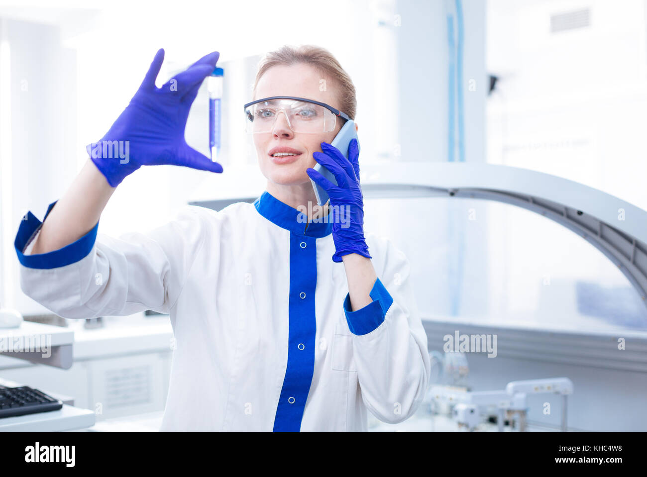 Glad positive scientist staring at glassware Stock Photo