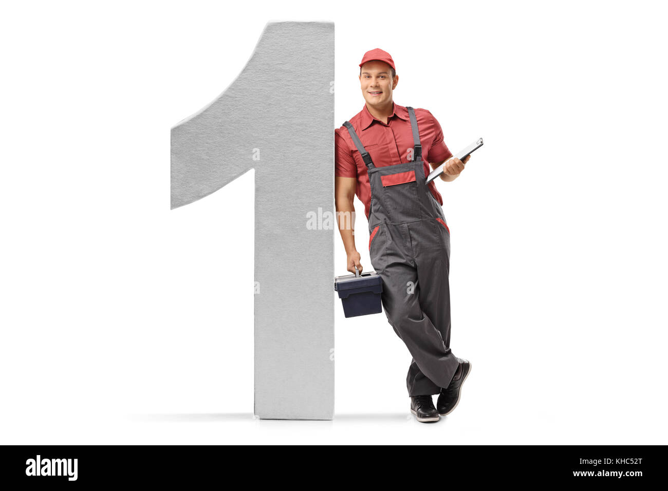 Full length portrait of a repairman with a clipboard and a toolbox leaning against a cardboard number one isolated on white background Stock Photo