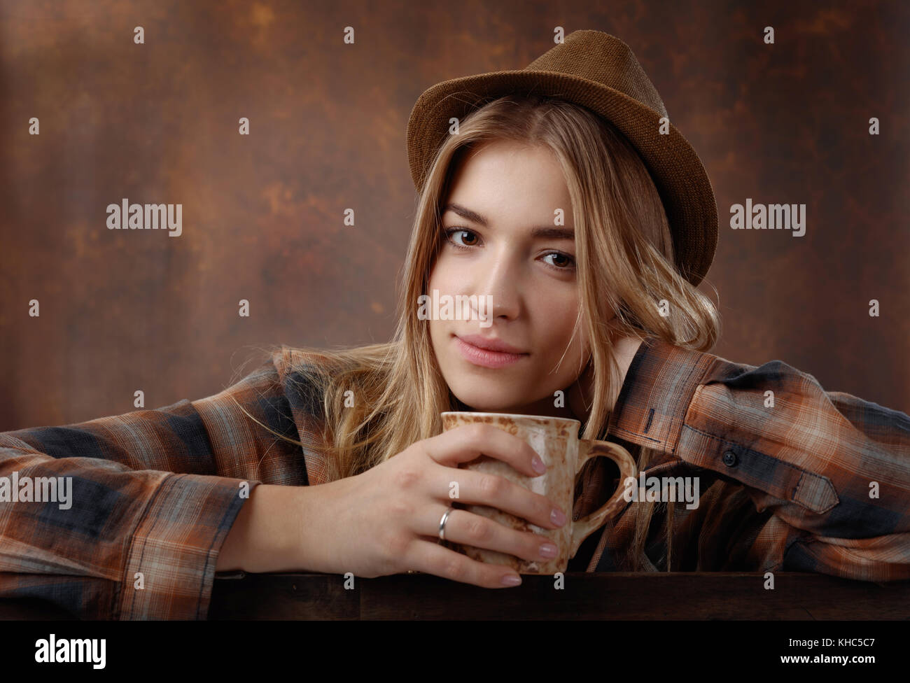 Young beautiful blonde in a brown plaid shirt with a mug of coffee . Stock Photo