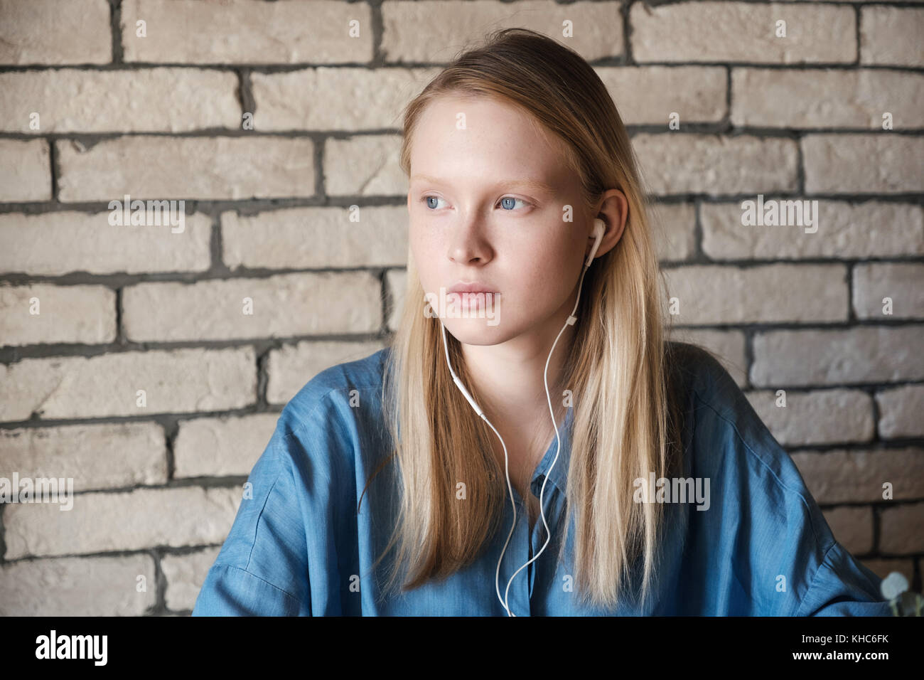Close up portrait of a young blonde with headphones in blue shirt at ...