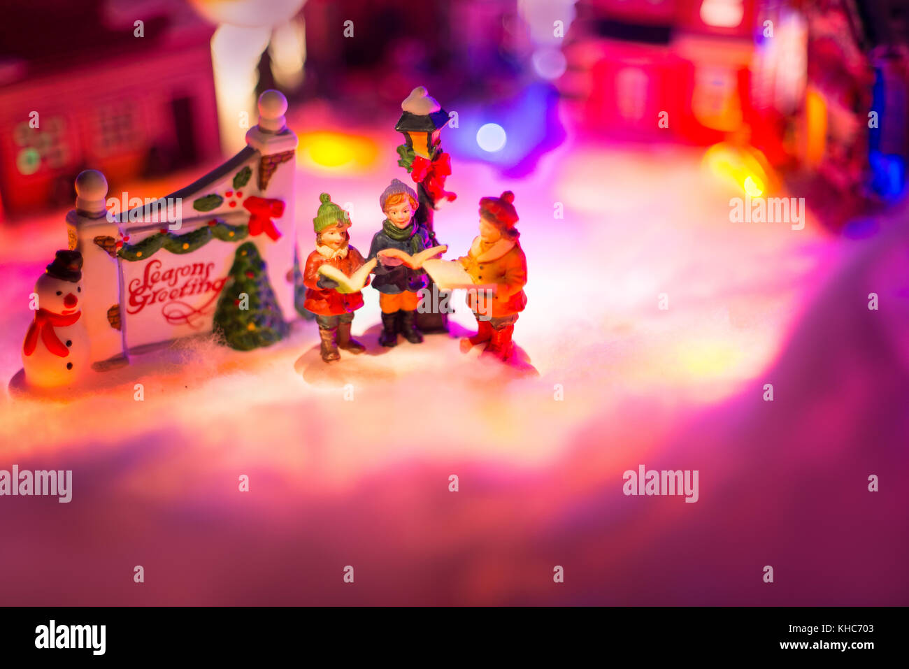 kid choir singing next to holiday greeting sign with snowy christmas village in the background. seasons greeting festive concept Stock Photo
