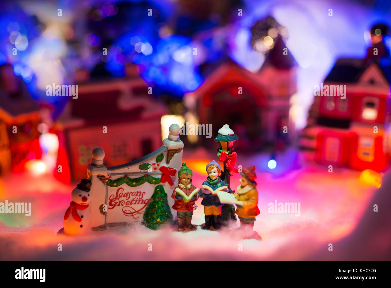 Christmas background with kids reading bible next to season greeting sign in front of snowy village Stock Photo