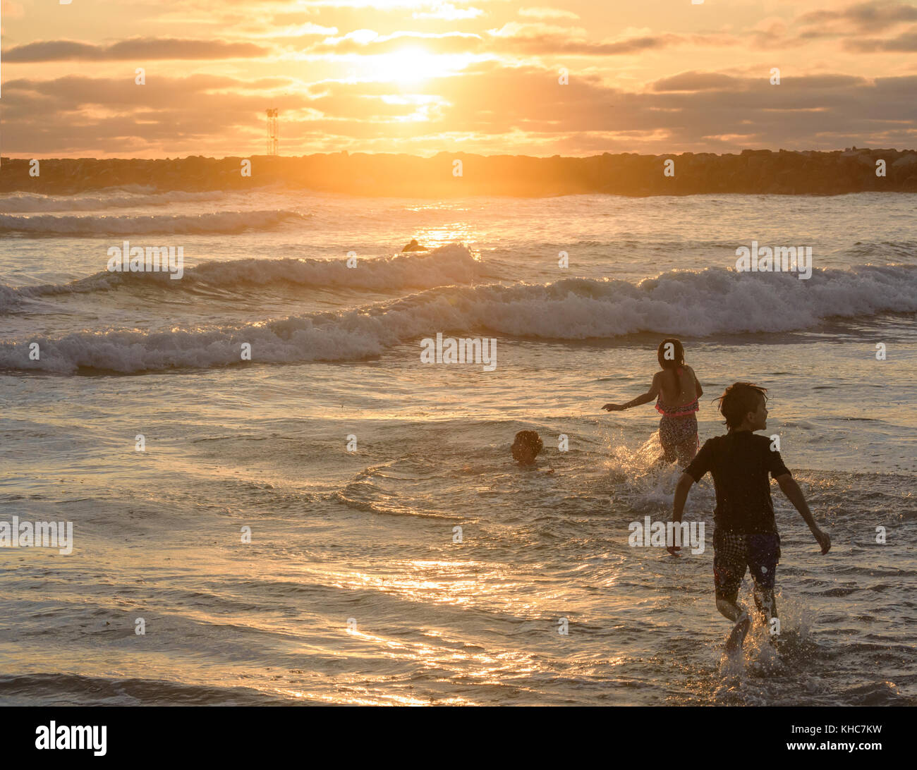 Kids play in the surf at sunset, Ocean Beach california Stock Photo
