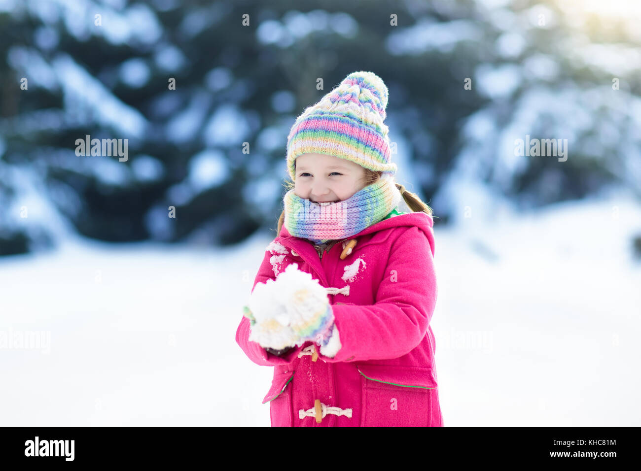 Child playing with snow in winter. Little girl in colorful jacket and ...