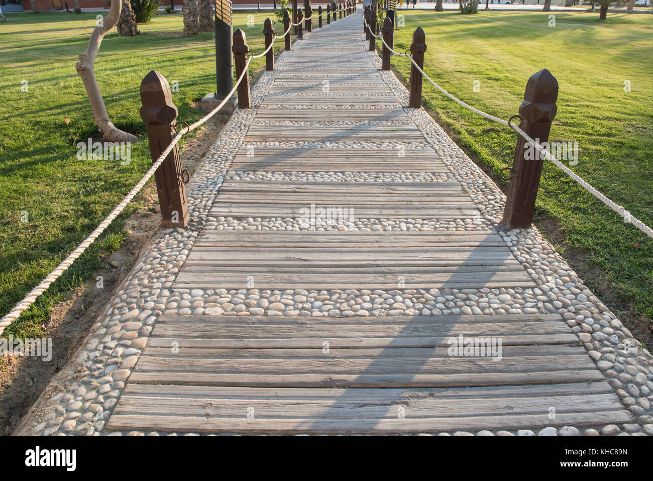 Ornate footpath through formal landscaped gardens with wooden posts in grounds of a luxury tropical hotel resort Stock Photo
