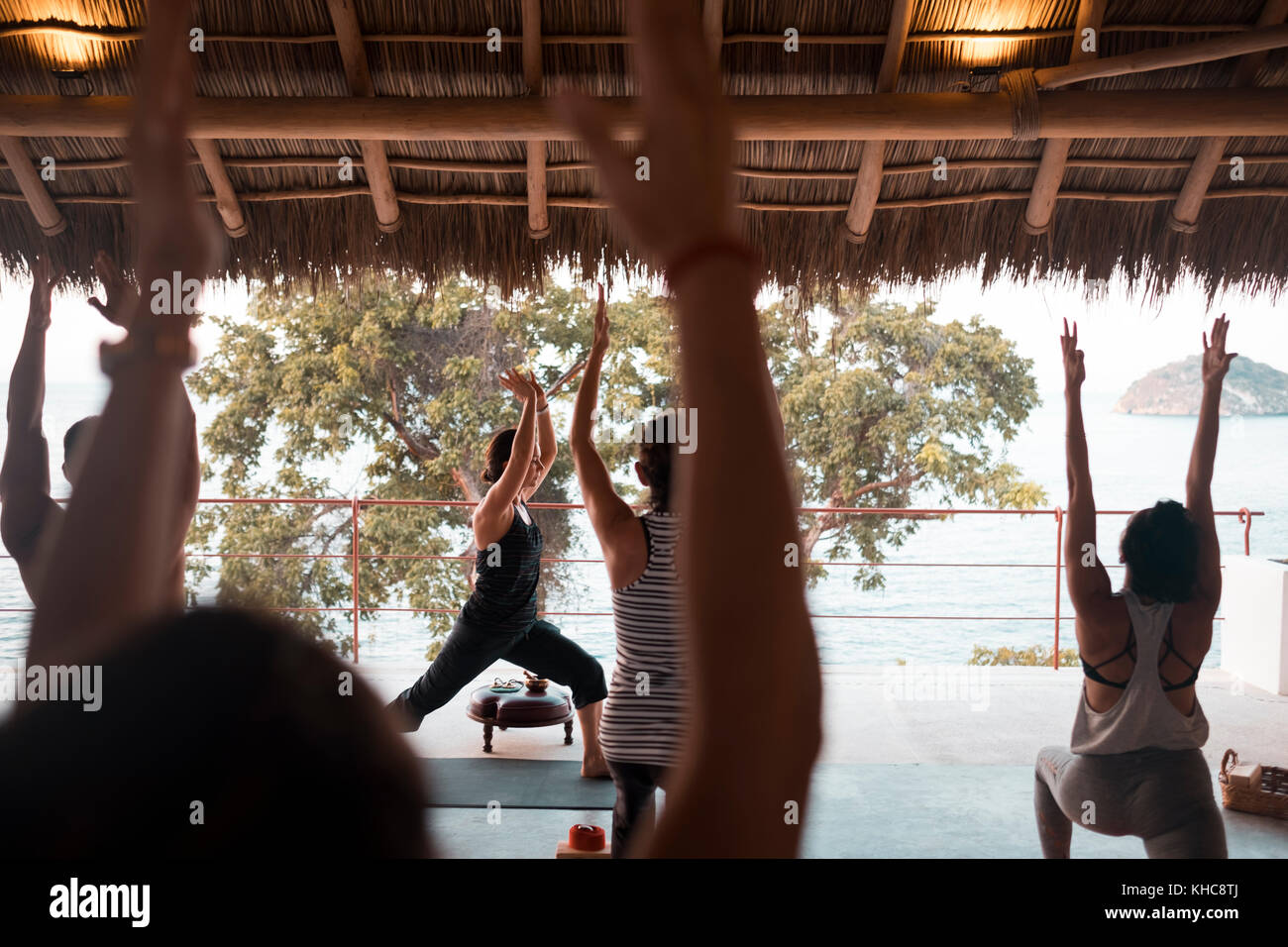 Group of multiple people practicing yoga on a palapa terrace. Yoga retreat Puerto Vallarta - Mismaloya, Mexico Stock Photo