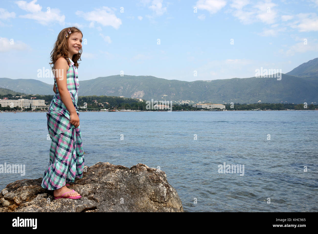 happy little girl standing on rock near sea Corfu island Stock Photo
