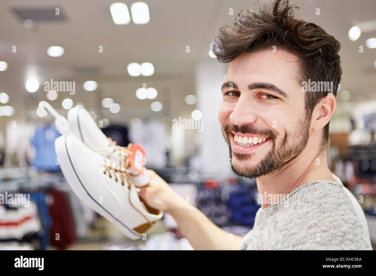 Happy young man is happy about matching shoes in fashion shop Stock Photo