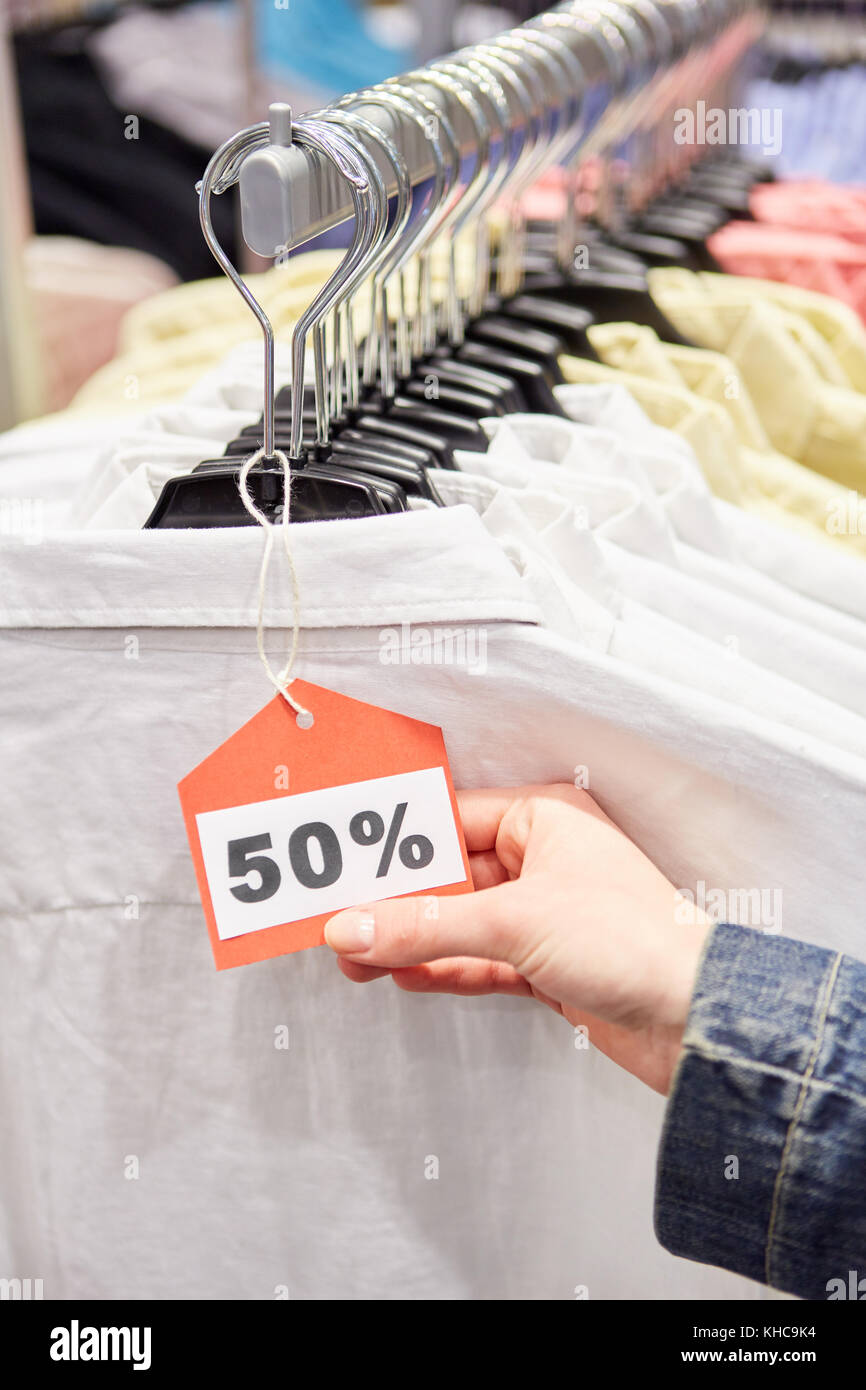 Hand holding price tag on clothes with 50 discount Discount in retail