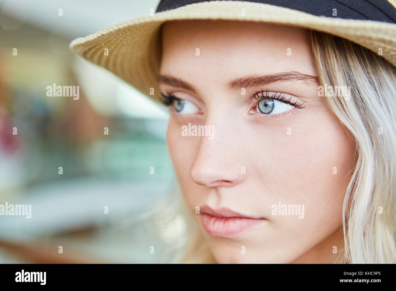 Young blond woman with straw hat looks melancholy Stock Photo