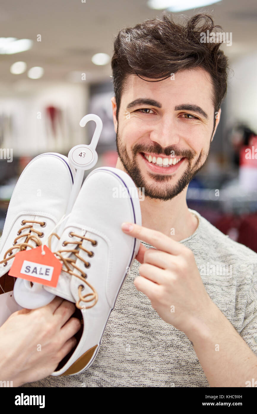 Young man as a customer buying shoes is looking forward to shopping