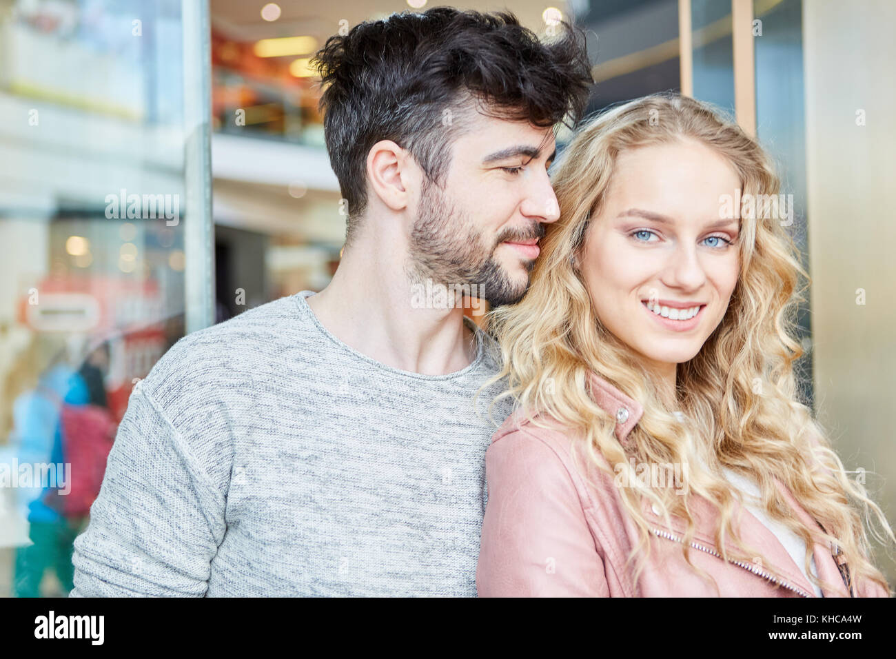 Young enamored teenage couple happily smiling in shopping mall Stock Photo