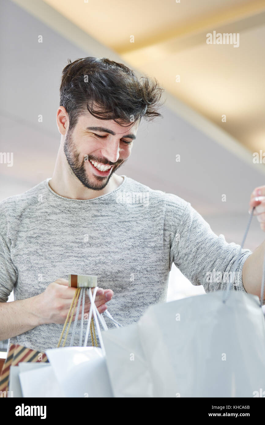 Young man looks happily in his pockets while shopping in shopping center Stock Photo