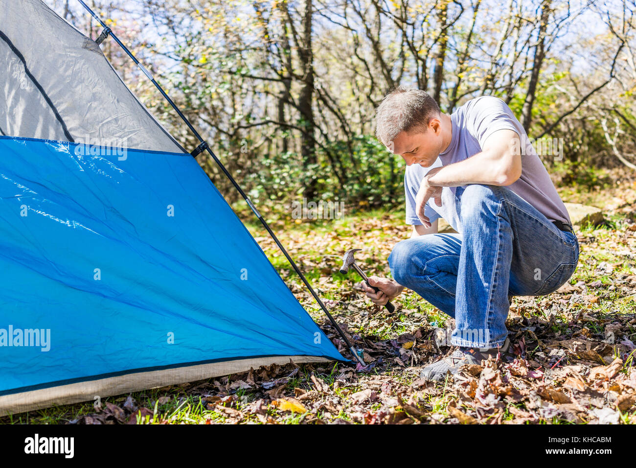 Young man setting up camp tent for camping trip on campground by Stock