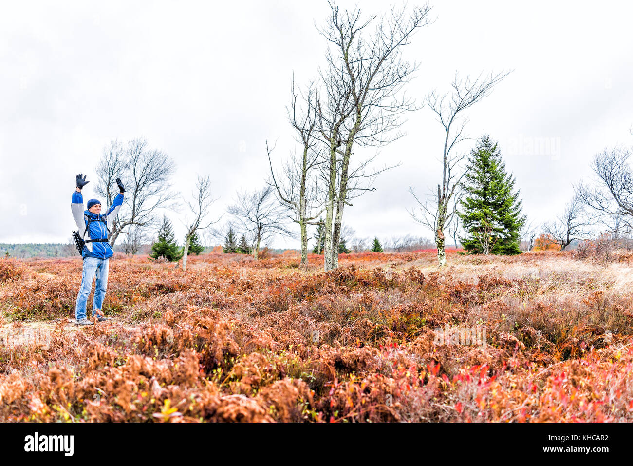 Young man walking on hiking trail through colorful orange foliage fall ...