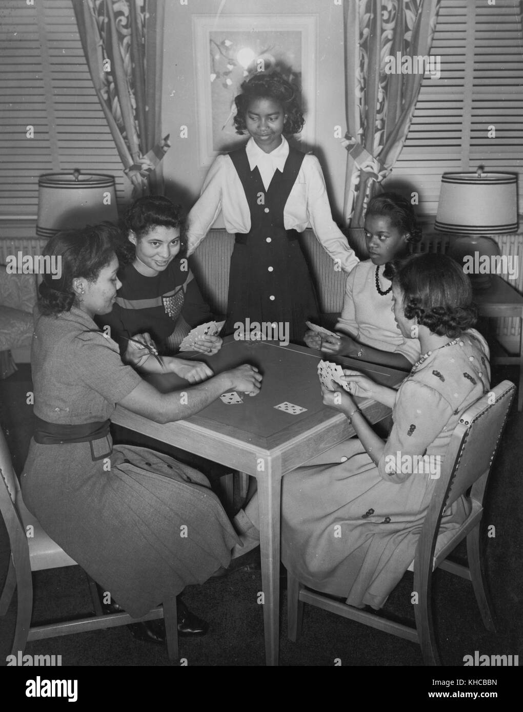 A group of young war worker-residents are shown enjoying a game of cards in the game room of the Lucy D Slowe Residence Hall, first government constructed hotels for African American women war workers, Washington, DC, 1942. From the New York Public Library. Stock Photo
