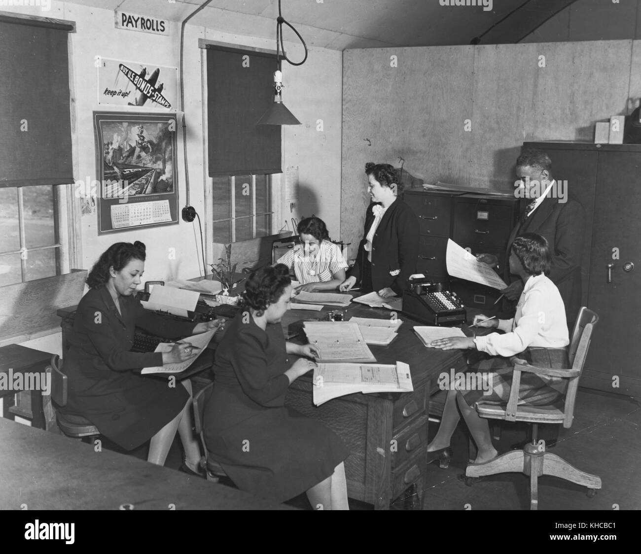 Office staff for Wake and Midway Halls, construction company creating housing for 1, 000 African American women war workers, left to right, clockwise, Zelda S Wilson, Mildred Dunn, Wilhelmena Barnett, Mrs Elnora Plato (wife of the contractor and his chief accountant), Mr Samuel Plato and Frances Purdy, Washington, DC, March, 1943. From the New York Public Library. Stock Photo