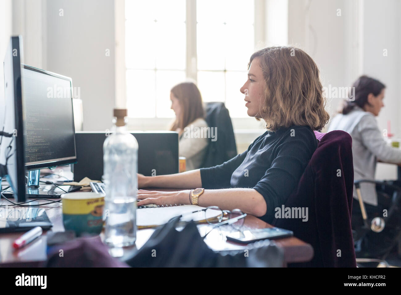 Yound devoted female software developers team working on desktop computer in IT statup company. Stock Photo