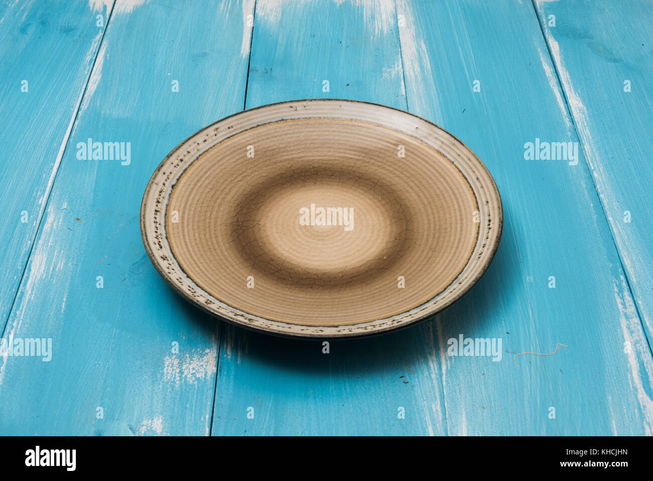 Round plate on blue wooden table with perspective side view Stock Photo