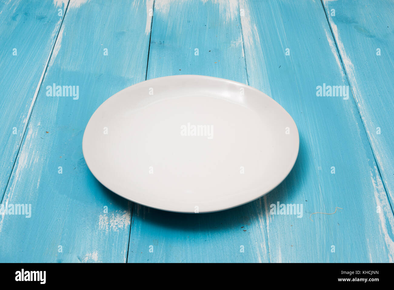 White Round plate on blue wooden table with perspective side view Stock Photo