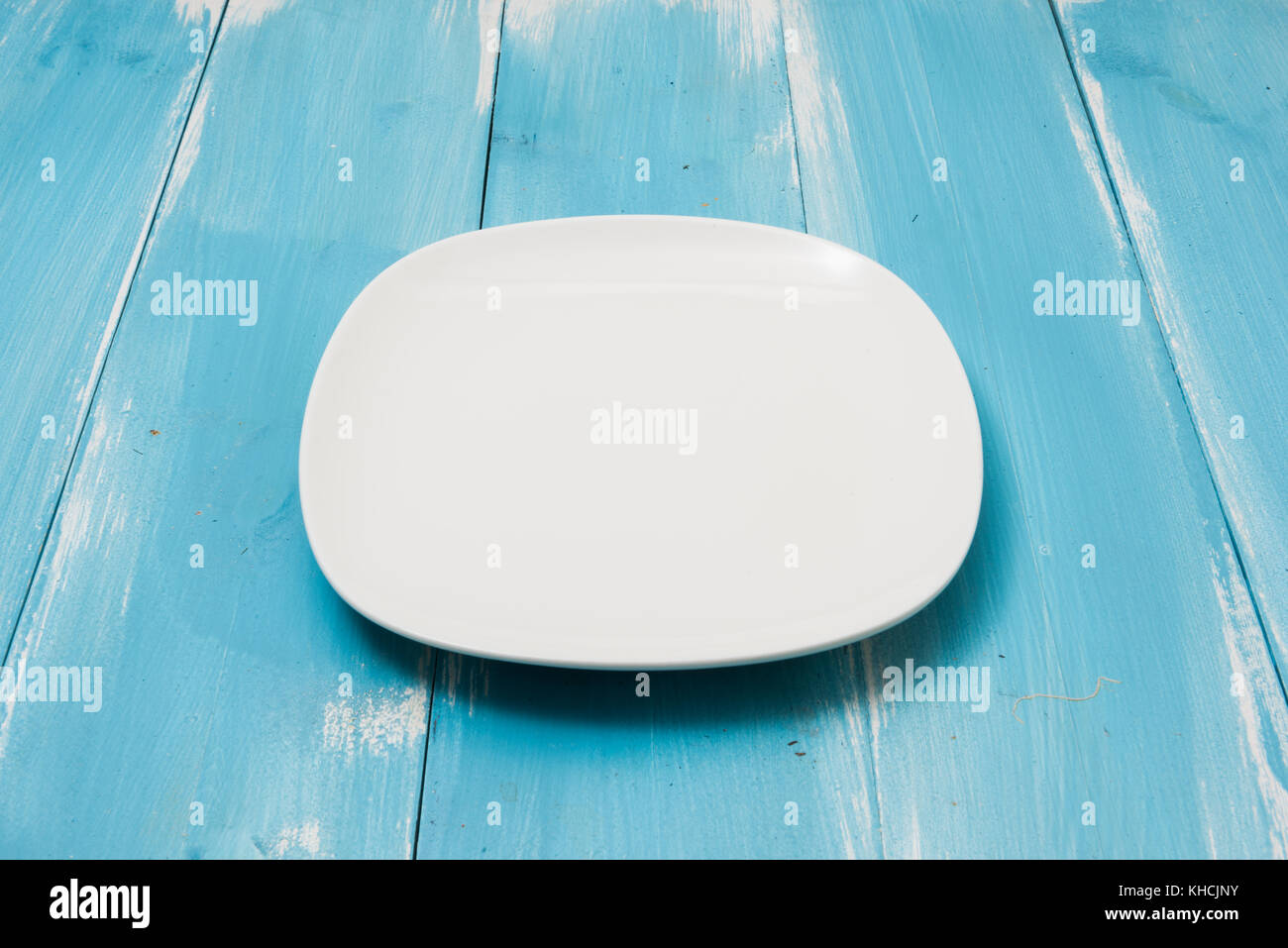 White plate on blue wooden table with perspective side view Stock Photo