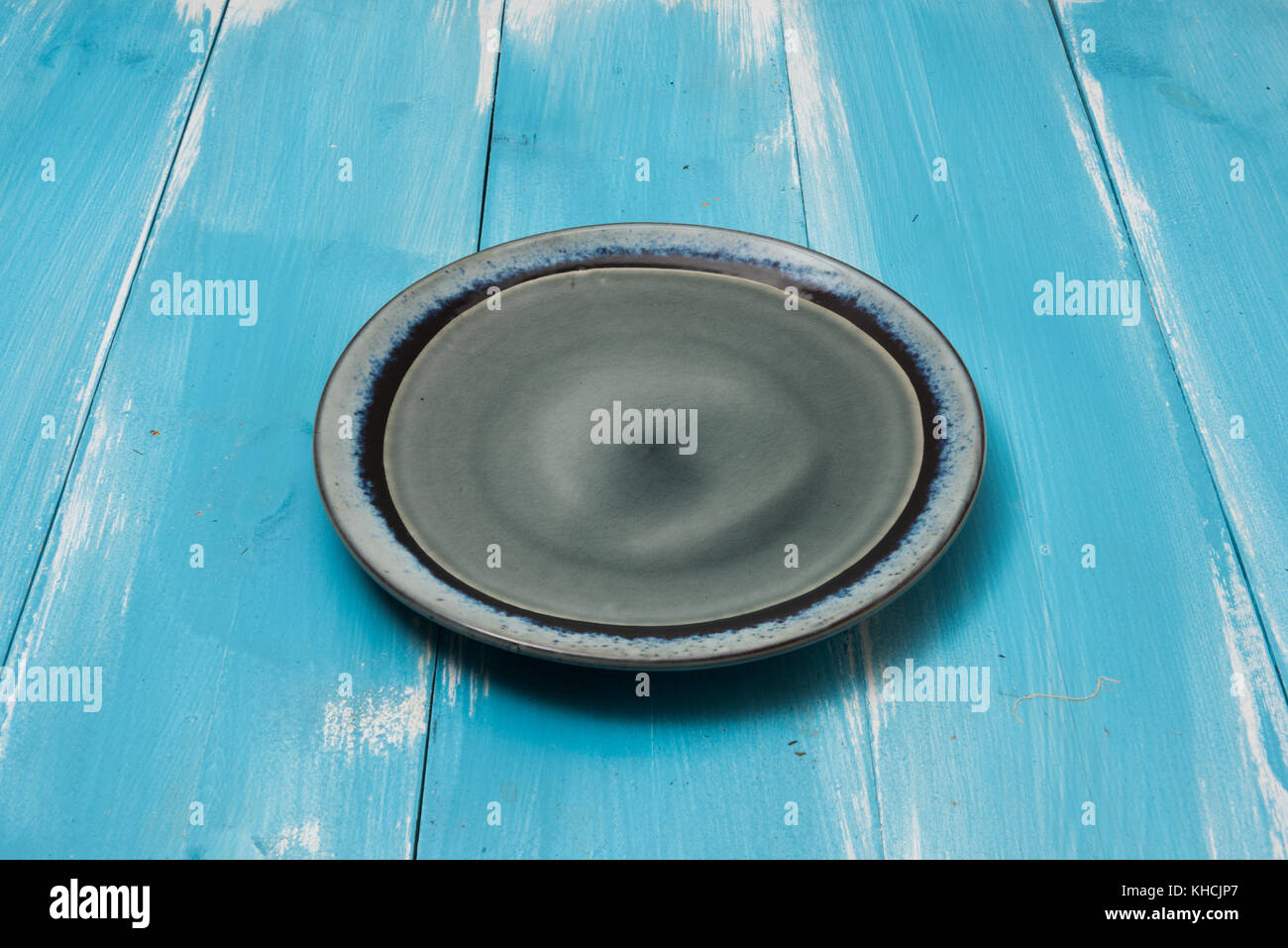 Round plate on blue wooden table with perspective side view Stock Photo