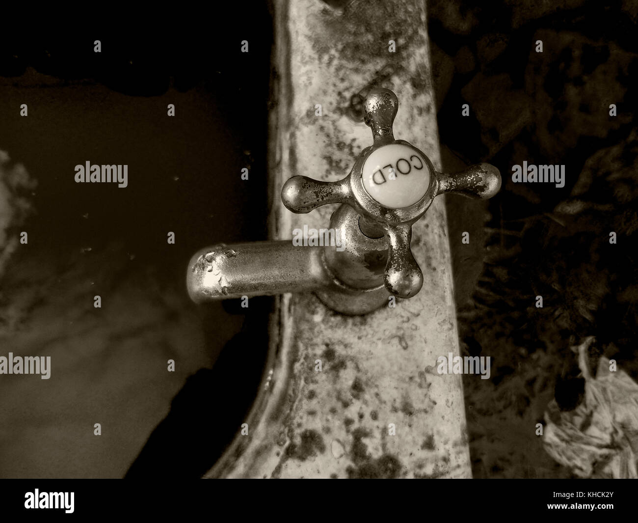 A chrome tap with a porcelain cold cap on a old cast iron bath with filthy water inside the bath. Left outside in the elements to slowly deteriorate. Stock Photo