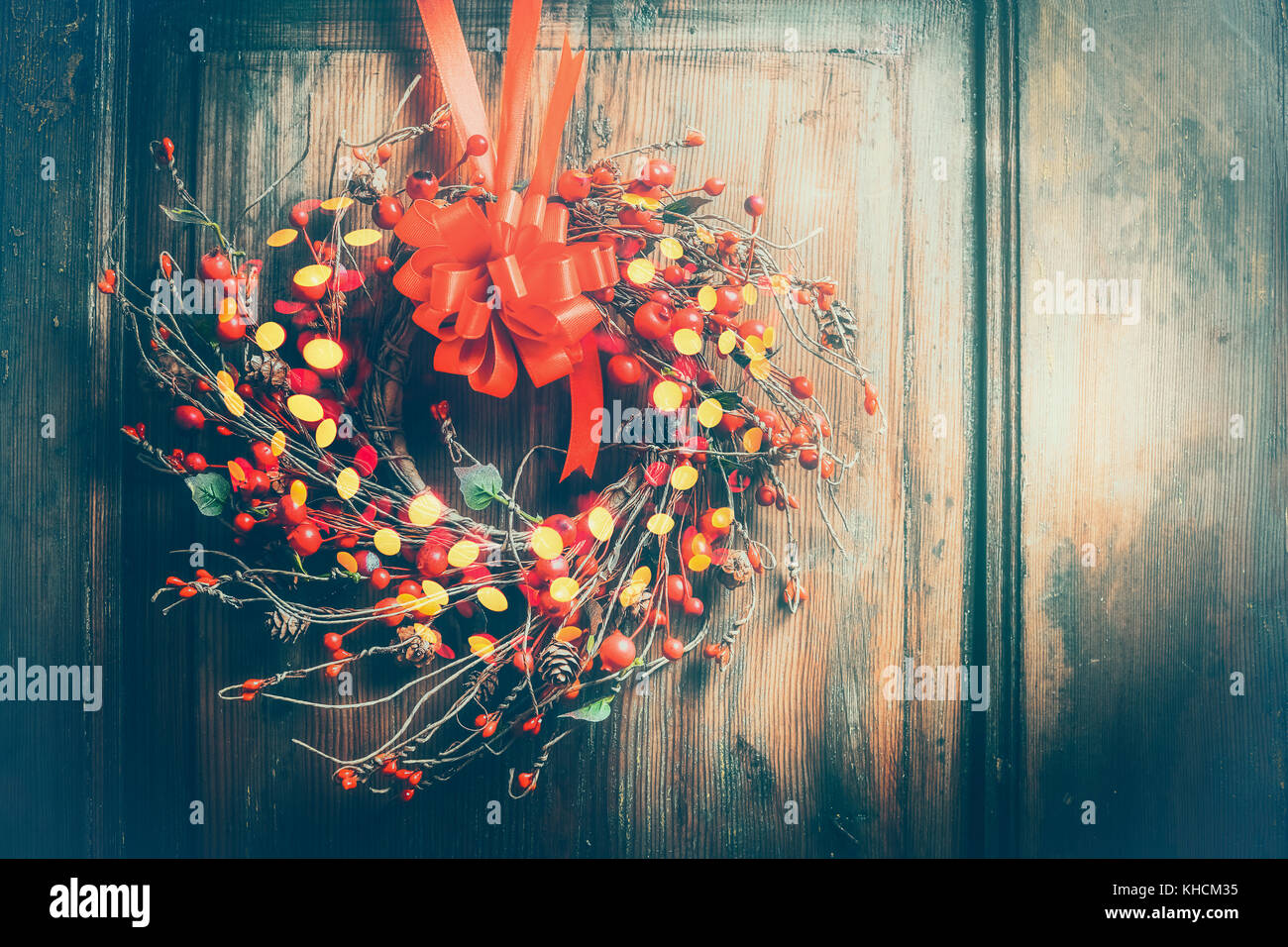Handmade Christmas wreath hanging on wooden door with red ribbon ...