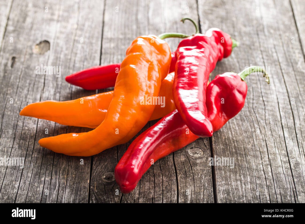 Orange and red peppers on old wooden table Stock Photo - Alamy