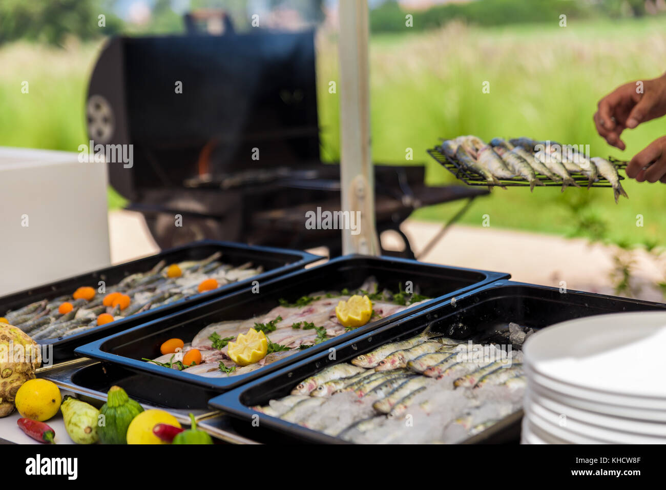 Chef putting sardines ready for barbecue as fire is lit and smoking Stock Photo