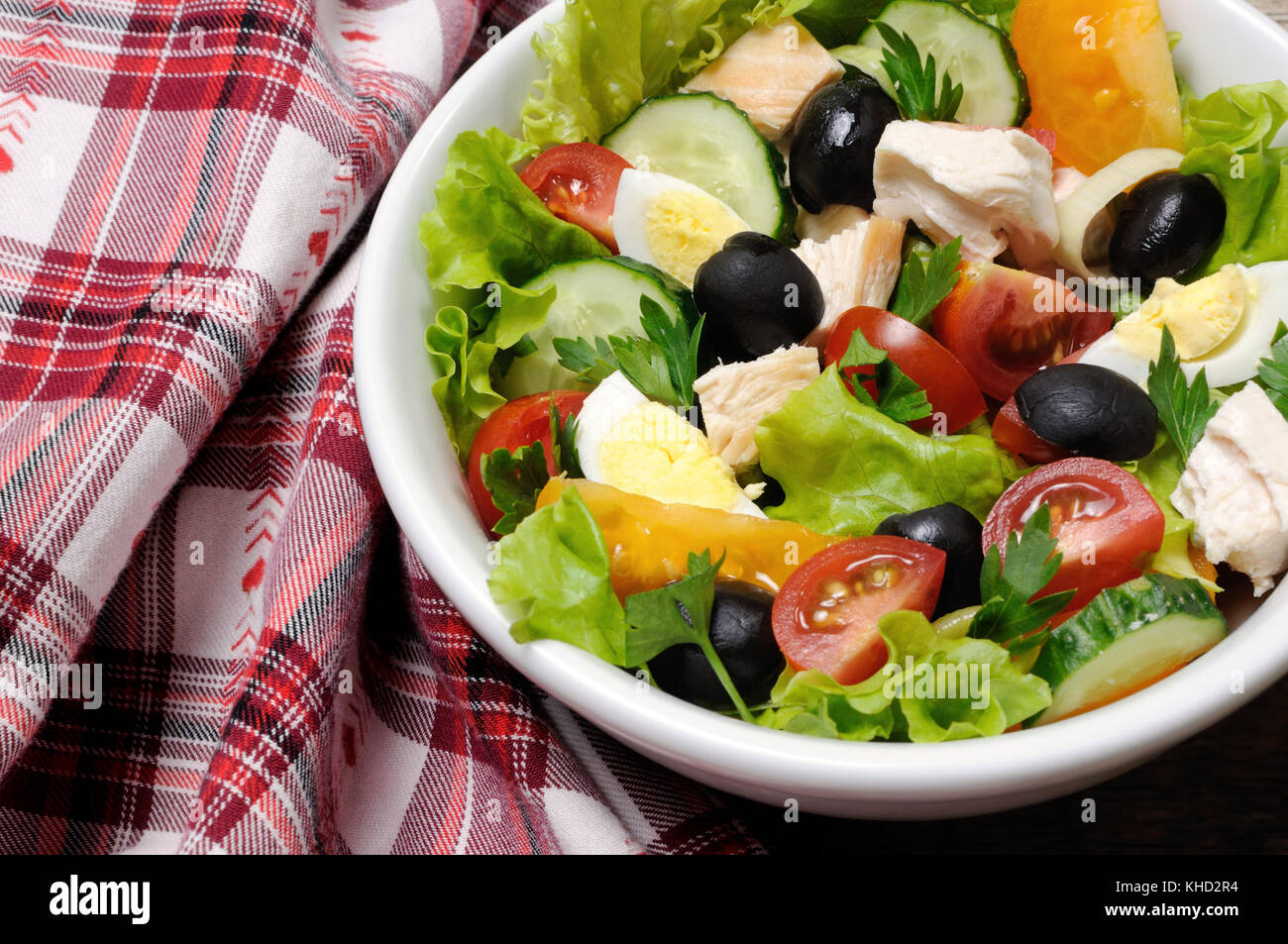 Vegetable salad with chicken and eggs, olives in lettuce leaves. Horizontal shot. Stock Photo