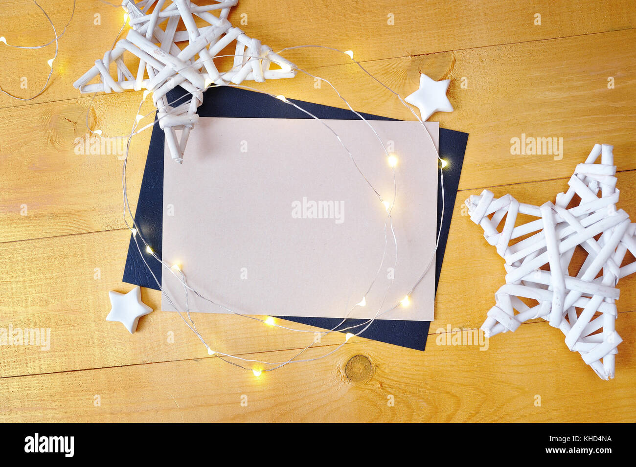 Christmas background kraft sheet of paper with place for your text and white christmas star and garland on a gold wooden background. Flat lay, top view photo mockup Stock Photo