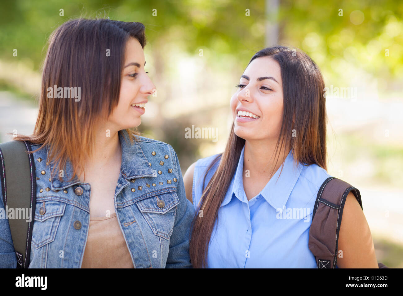 Two Beautiful Young Ethnic Twin Sisters With Backpacks Walking Outdoors. Stock Photo
