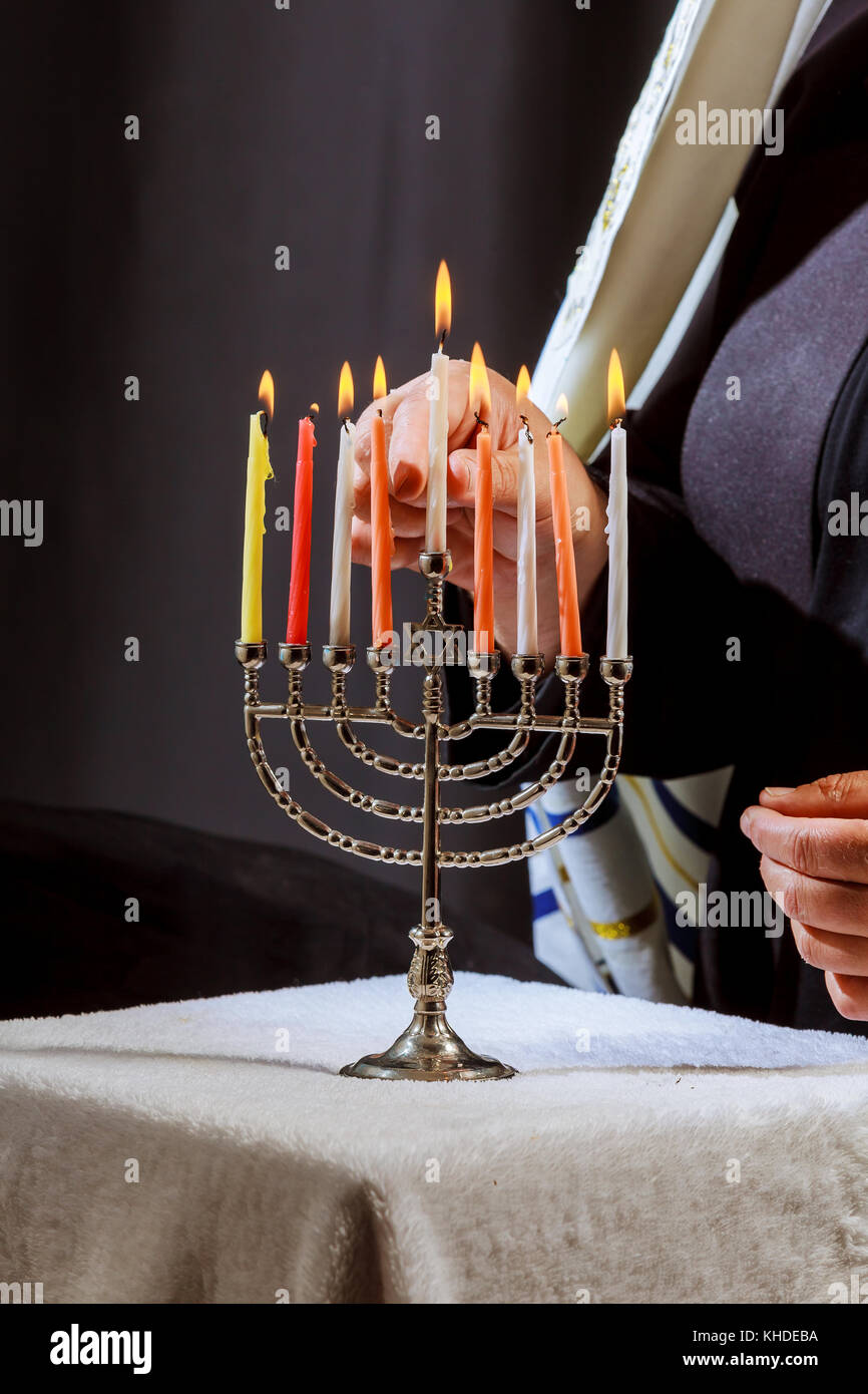 man hand lighting candles in menorah on table served for hanukka man lights candles Stock Photo
