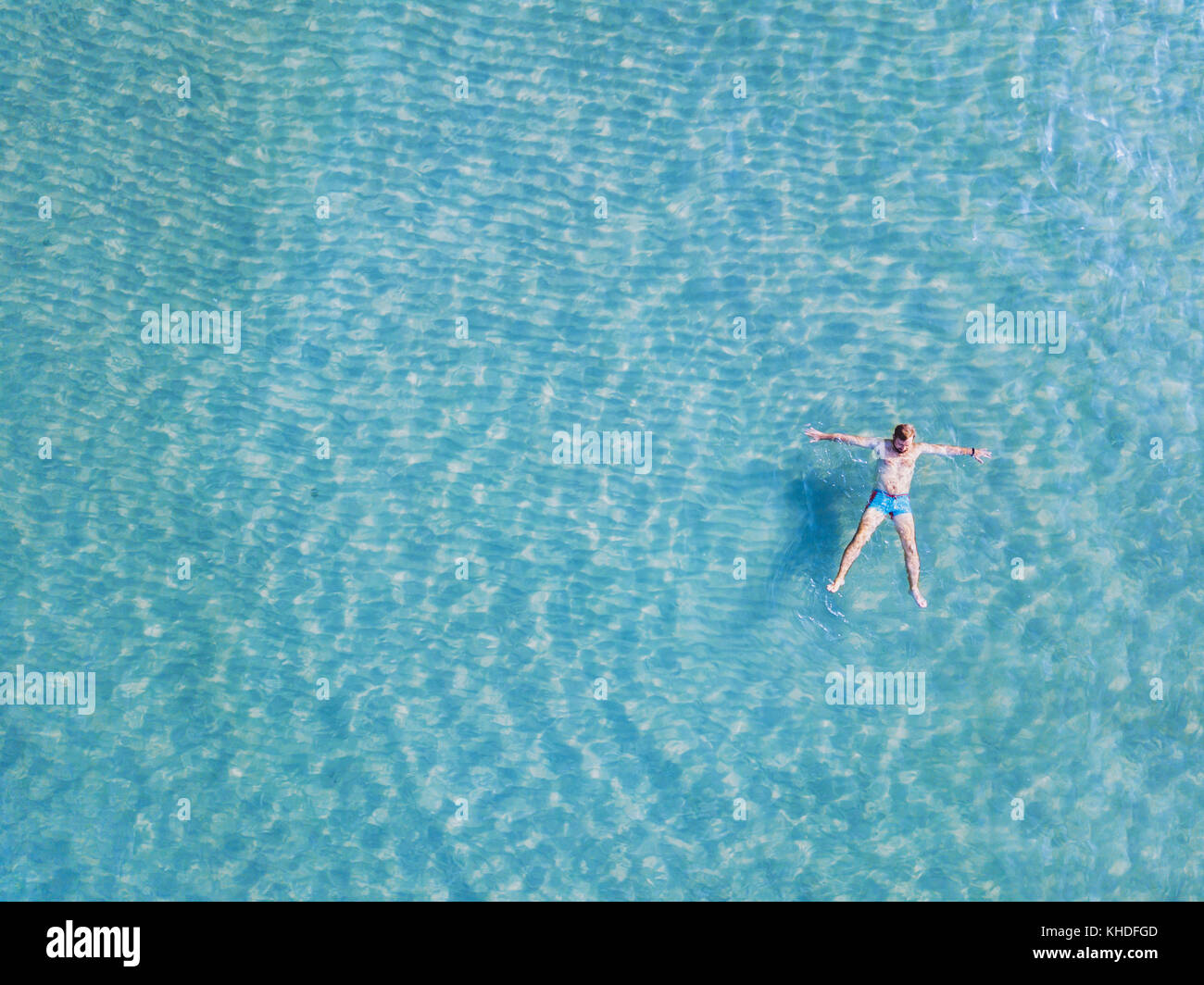 man swimming in turquoise water from above, top view of tourist relaxing in the sea on paradise beach with copy space Stock Photo