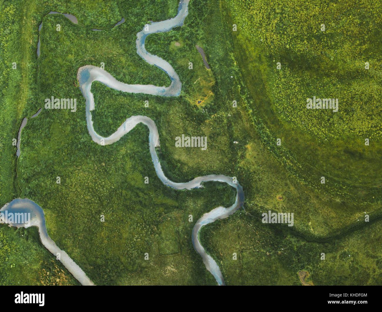 aerial landscape of winding river in green field, top view of beautiful nature texture from drone Stock Photo