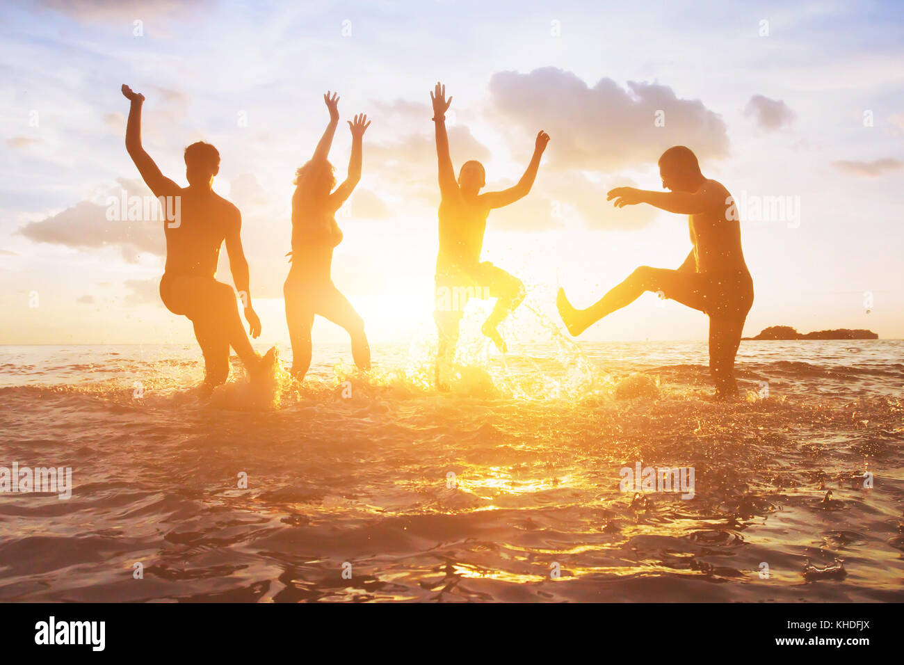 crowd of friends having fun in the water at sunset, silhouettes of happy people enjoying summer holidays Stock Photo