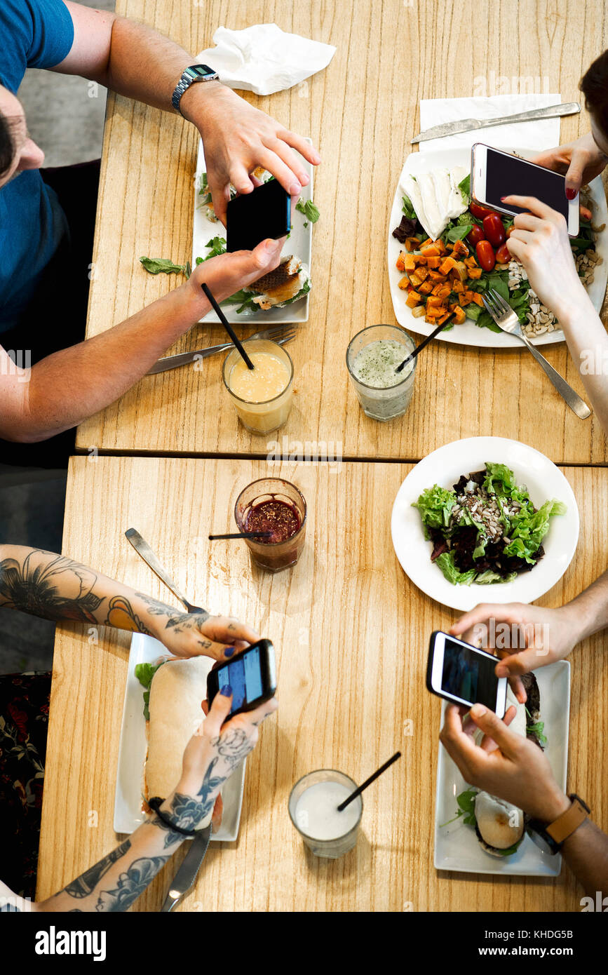 Diners using smartphones in restaurant, cropped overhead view Stock ...