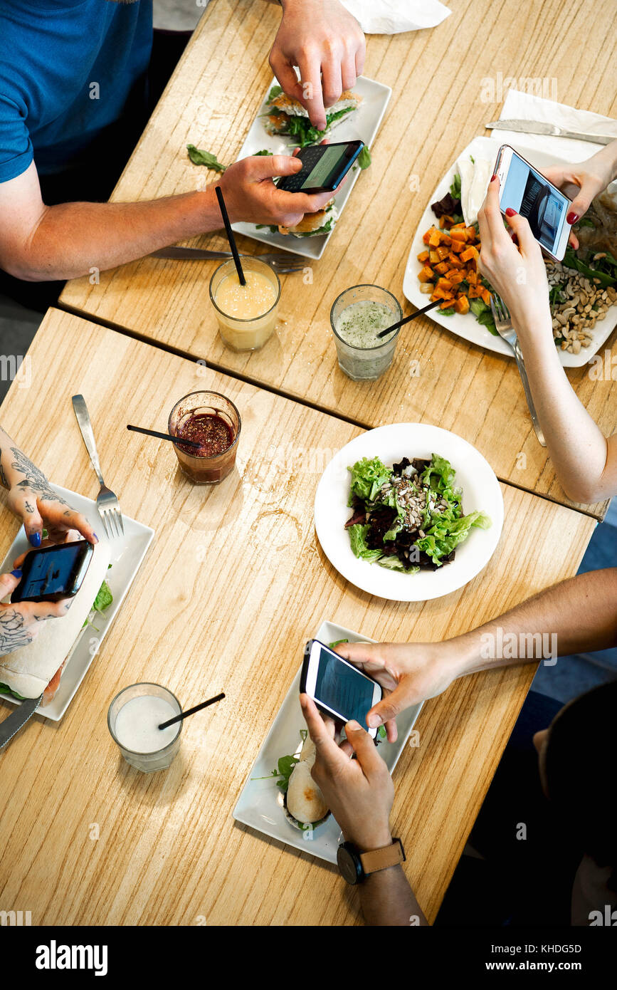 Diners using smartphones in restaurant, cropped overhead view Stock ...