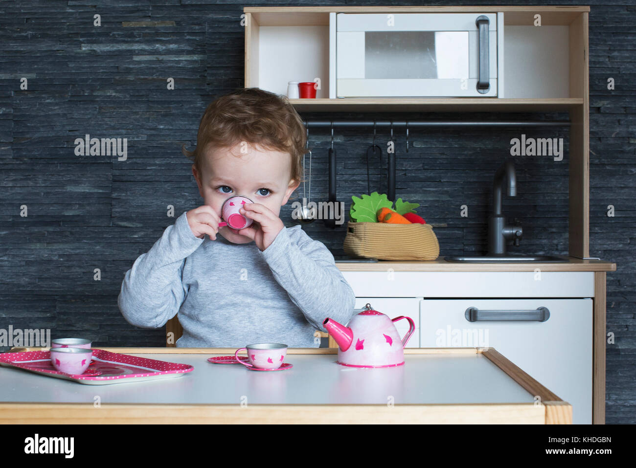 Little girl playing with toy tea set Stock Photo - Alamy